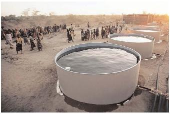The Food-for-Work program offers food to hungry people in exchange for work they do to improve vital infrastructure. Here, Somalis gather around water tanks, which were built to stabilize the water supply for drinking and irrigation in the drought-afflicted country. [© Kevin Fleming/Corbis. Reproduced by permission.]